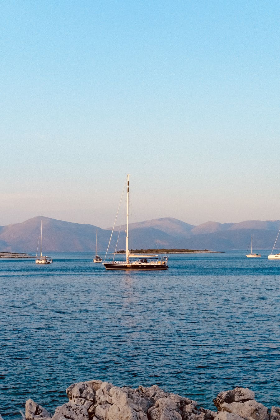 A sailboat at anchor in a calm bay at golden hour