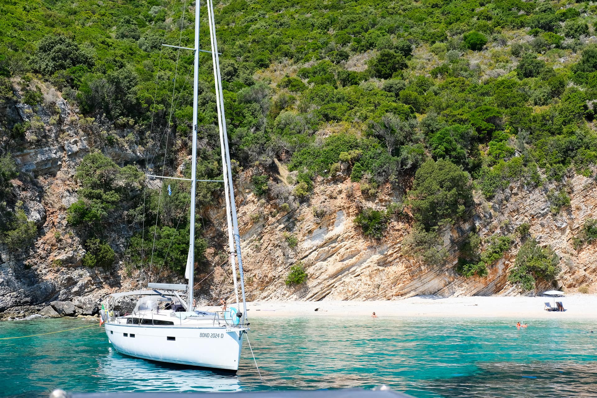 A sailboat anchored in a turquoise bay off the Ionian coast