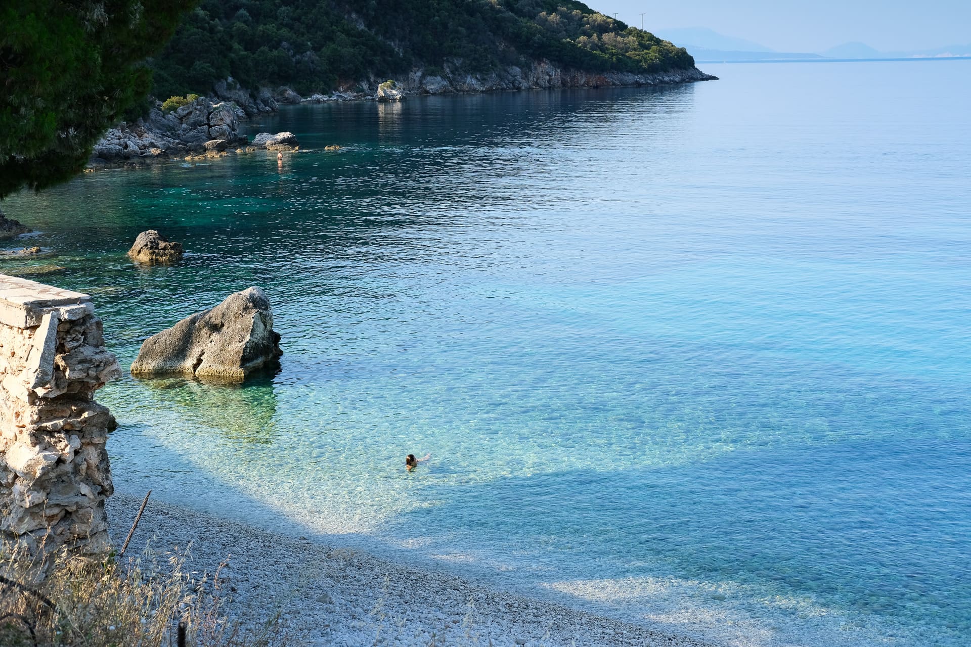 A swimmer in a clear turquoise cove on the Ionian coast